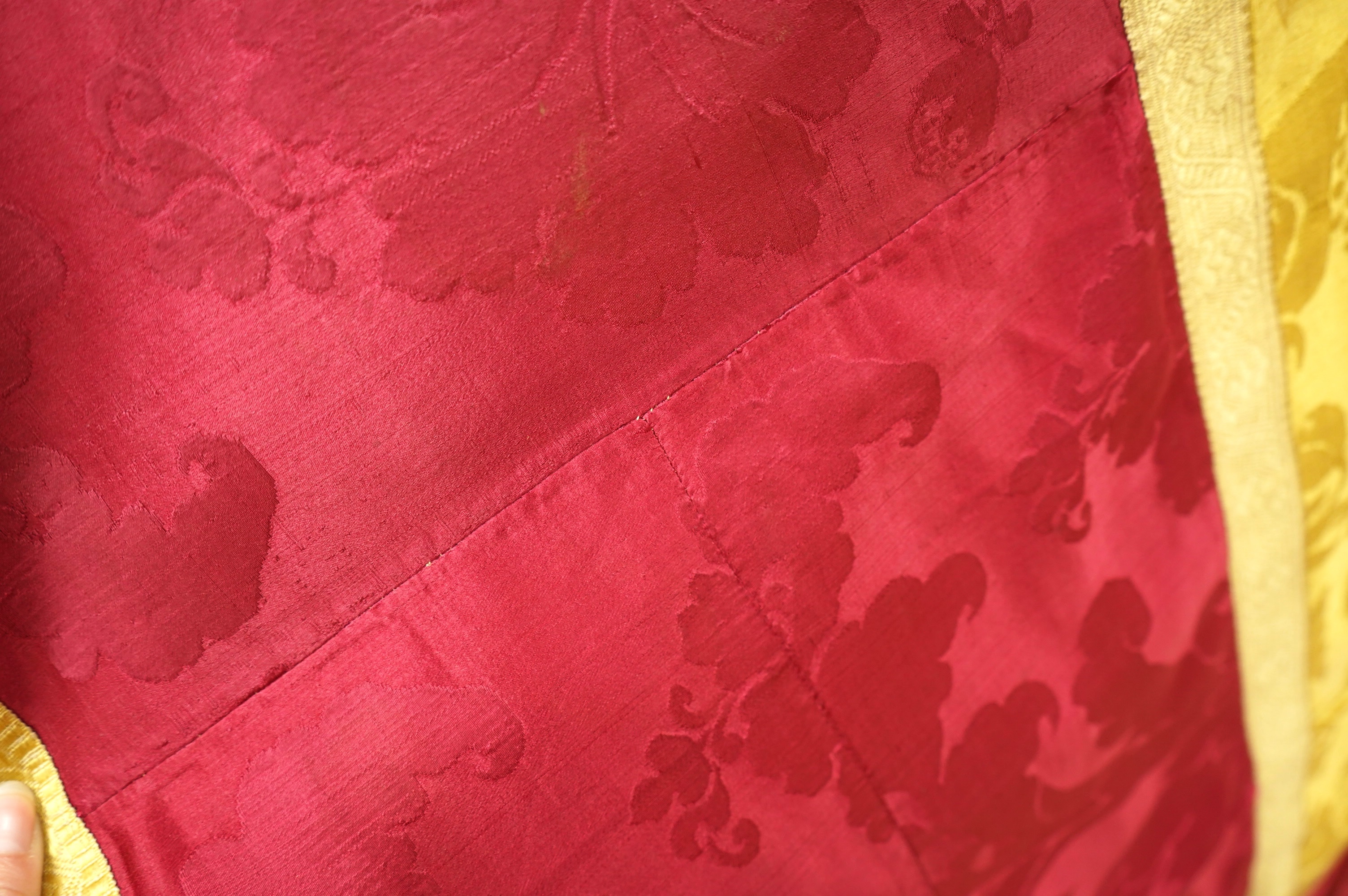 A 19th century gold and crimson silk damask bed cover, the centre being short loom widths of gold damask in a large repeating design, the outer panel a similar crimson damask, both finished with decorative gold braid bor